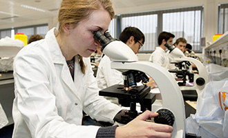 A Medicine (BM BCh) student from University of Oxford is studying by using a microscope.